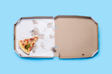 slice of hot fresh pizza lies in a cardboard package on a blue background. Top view, flat lay