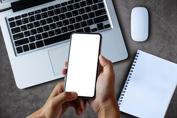 Male hands working on modern smartphone and laptop. Office desktop on Gray concrete wall background.