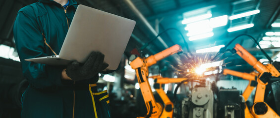 Engineer use advanced robotic software to control industry robot arm in factory . Automation...