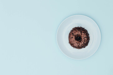 Chocolate donut on a blue plate and a blue background.