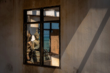The buddha in the old church, seen through the window in a temple at Prachuap Khiri Khan province in Thailand