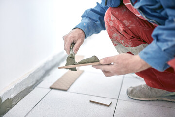 Professional ceramics tile man worker placing new tiles on the floor and wall.