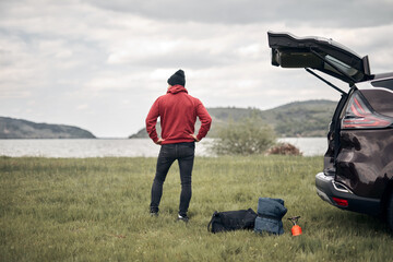Camper packing and unpacking from a car's back door in nature.