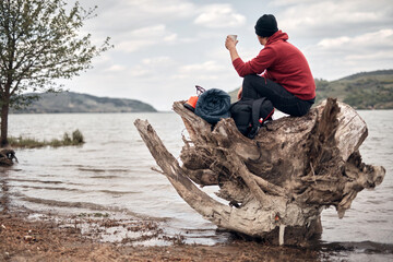 Hiker camping in nature on a river shore.