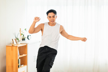 Fototapeta na wymiar Happy Asian young man Doing Exercises and dancing at Home