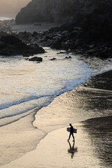 Trevaunance Cove at dawn as a lone surfer walks out to go surfing, Cornwall, England
