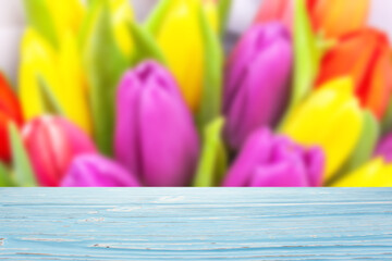Blue wood table top on blur bouquet of colorful tulips background