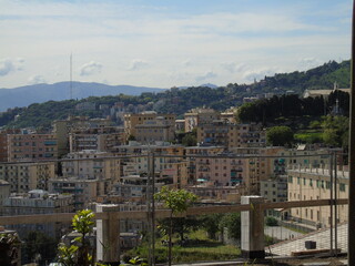 Obraz premium Genova, Italy - May 09, 2021: Panoramic view of the port Genoa, Italy. View from the sea to the old town, and the port on spring sunny day. Genoa bay, harbor, yacht at the pier. Tourist destinations.