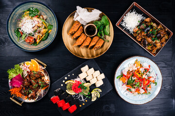 Asian food cooking. Wok, noodles and vegetables salad and chopsticks on dark rustic background