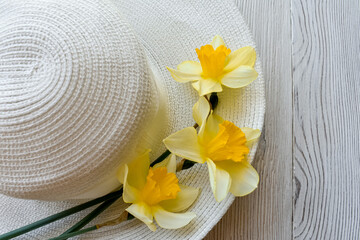 Flowers, yellow daffodils on a white hat, wooden boards. Close-up.