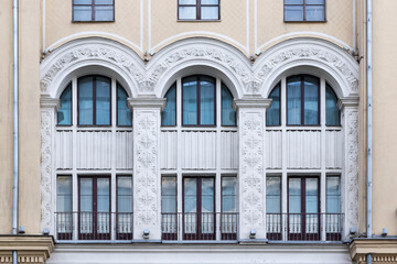 Fototapeta na wymiar Soviet architecture classical facade building front view. Three big arched windows decorated with stucco moulding architectural details.