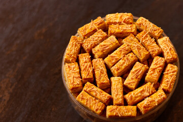 Crispy kastengel cookies in a jar on dark wooden table. Kastengel or kaasstengels is Dutch influenced-Indonesian cheese cookies. It usually served in Ramadan, Eid Al-Fitr and Eid Al-Adha.