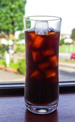 Japanese style ice coffee (black coffee with ice cubes) in a long glass on a window sill 