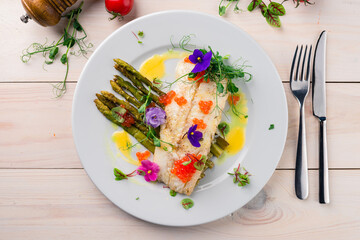 Fish fillets with asparagus and slice of lemon on a plate