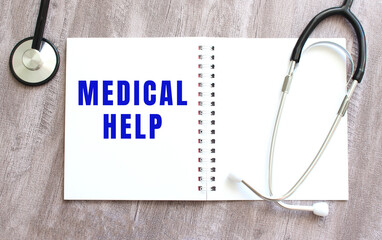 A white notebook with the words MEDICAL HELP and a stethoscope on a gray wooden table.