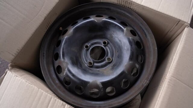 Closeup view 4k stock video footage of opened cardboard delivery box and old used steel wheel rims bought online through internet. Driver just received them in post office of delivery service