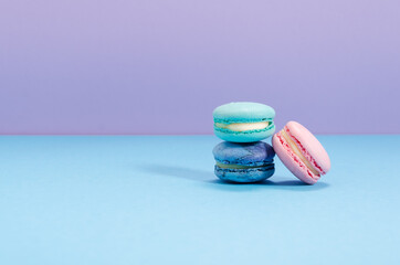 Three pink, green and blue macaroons on a blue and lavender copy space background. 