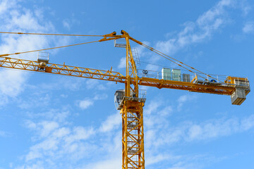 Construction tower crane with cab on blue sky background