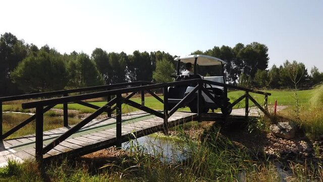 Carrito de golf pasando por un puente sobre un arroyo