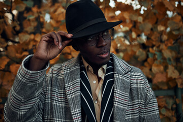 Obraz premium Portrait of fashionable handsome young dark skinned gentleman wearing layered elegant outfit posing outdoors, waiting for his date. People, beauty, elegance, style, fashion and trendy clothing