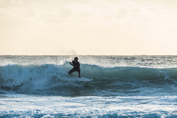 Young surfer riding a wave at sunset