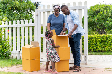 Happy African American family carry cardboard box for moving new house on moving day, Young back girl find personal belongings.