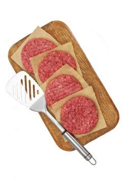 Minced Raw Steak Burgers from Beef Pork Meat on Cutting Board Isolated on White Background, Overhead View. Uncooked Ground Meat Patties for Grilling. Burgers for BBQ Grill and Spatula, Top View.