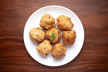 Plain dry dahi badhe for preparation of chaat, Garnished with cumin and green fresh coriander over wooden background.
