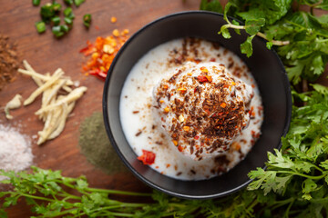 Chaat Dahi vada (AKA Dahi Bhalla, Doi Bora, mosaru vade, Dahi Bara, thayir vadai, perugu vada). Prepared by soaking vadas in thick curd (yogurt). Garnished with cumin and green fresh coriander
