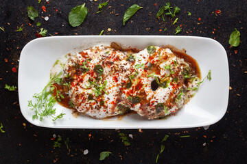 Chaat Dahi vada (AKA Dahi Bhalla, Doi Bora, mosaru vade, Dahi Bara, thayir vadai, perugu vada). Prepared by soaking vadas in thick curd (yogurt). Garnished with cumin and green fresh coriander
