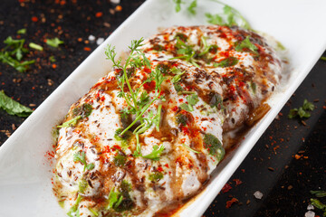 Chaat Dahi vada (AKA Dahi Bhalla, Doi Bora, mosaru vade, Dahi Bara, thayir vadai, perugu vada). Prepared by soaking vadas in thick curd (yogurt). Garnished with cumin and green fresh coriander