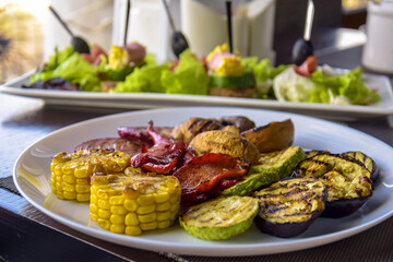 Healthy food. Delicious grilled vegetables (zucchini, eggplant, bell pepper, onion, corn and mushroom) are served in white plate. Close-up. Selective focus.