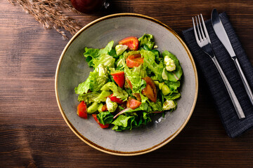 Fresh green salad in bowl on wooden table