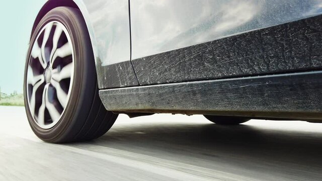 Dirty muddy sports car with low view of the tires speeding fast on the empty highway