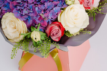 Bouquet in a box with anemones, roses, hydrangea and harmonized with greenery.
