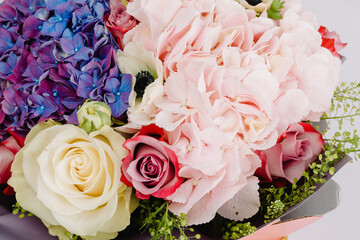 Bouquet in a box with anemones, roses, hydrangea and harmonized with greenery.