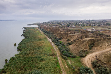 Fototapeta na wymiar Aerial view of a path along huge lake with beautiful sand dunes and green shore
