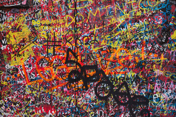black wall is painted with small multi-colored graffiti