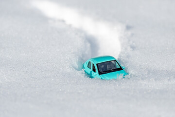 only the roof of the toy car sticks out of the snow