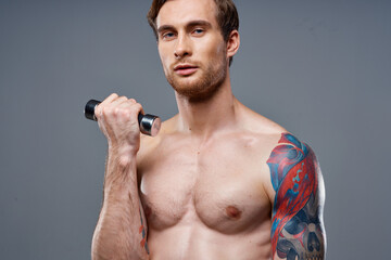 sporty male bodybuilder with pumped up arm muscles and color tattoo dumbbell biceps