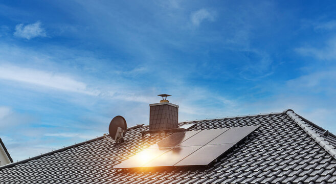 Hausdach mit schwarzen Dachziegeln und Photovoltaikanlage