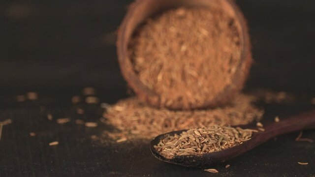 cumin seeds isolated on black background,wooden bowl blurry background selective focus on small Cumin seeds,wooden spoon on carvi