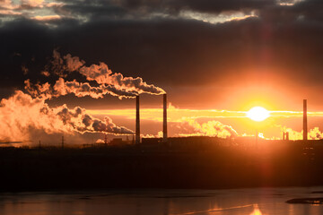 in the rays of the bright setting sun an enterprise with smoking chimneys