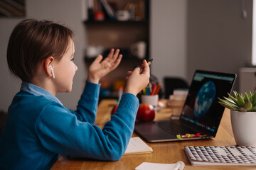 Fototapeta na wymiar A Preteen boy uses a laptop to make online classes, globe on the screen, making notes