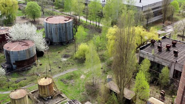 Old industrial territory. Abandoned buildings of ancient factory. Ruined edifices in spring. Old brick pipe of industry. Aerial view.
