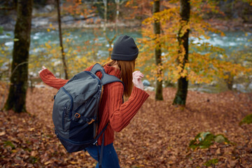 Fototapeta premium woman with backpack travel tourism forest landscape park river fallen leaves side view
