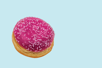 Close up view of pink  donut sprinkled with white glaze isolated on blue background. Food and drink concept.