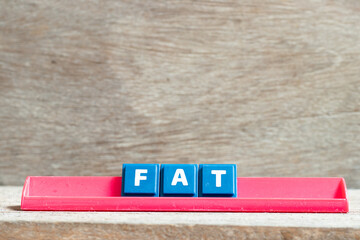 Tile letter on red rack in word FAT (Obesity or abbreviation of factory acceptance test, file allocation table) on wood background