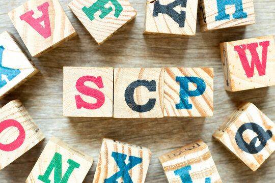 Alphabet letter block in word SCP (Abbreviation of .Service control point, Supply chain planning, Standard corporate protocol or Salary continuation plan) with another on wood background