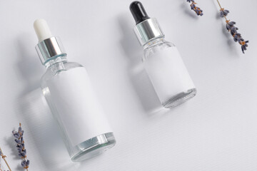 Cosmetics boottle with pipets with lavender flower on white background.